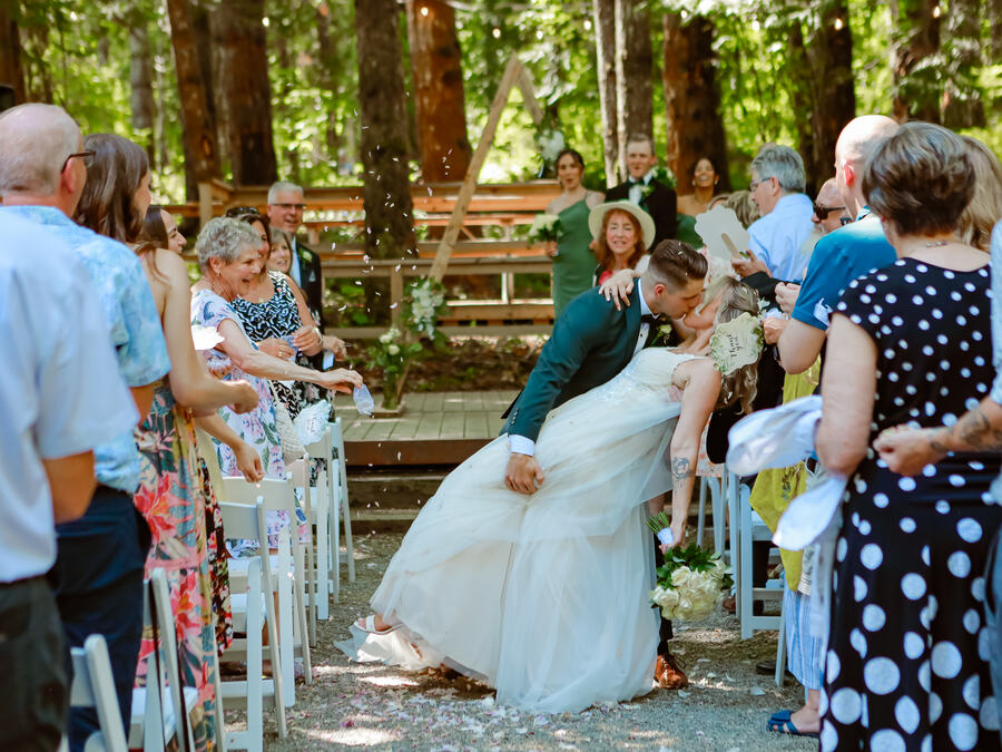 A wedding ceremony among the trees at McLean Mill near Port Alberni, with guests celebrating the newlyweds